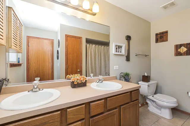 a bathroom with a double vanity sink toilet and a mirror