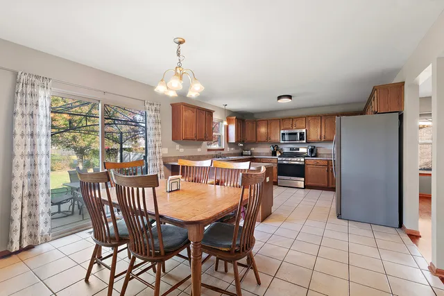 a dining room with furniture a chandelier and kitchen view
