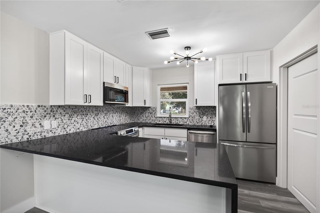 1503 Canal Court Tavares, FL 32778 - Photo 11 of 41 a kitchen with granite countertop a refrigerator sink and microwave