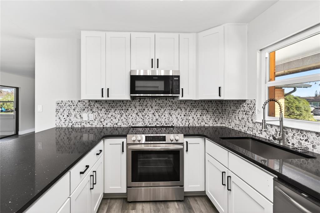 1503 Canal Court Tavares, FL 32778 - Photo 12 of 41 a kitchen with granite countertop white cabinets and white appliances