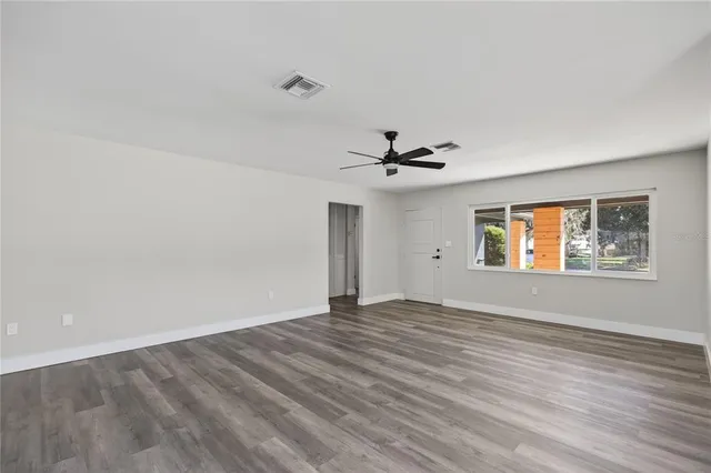 a view of an empty room with window and wooden floor