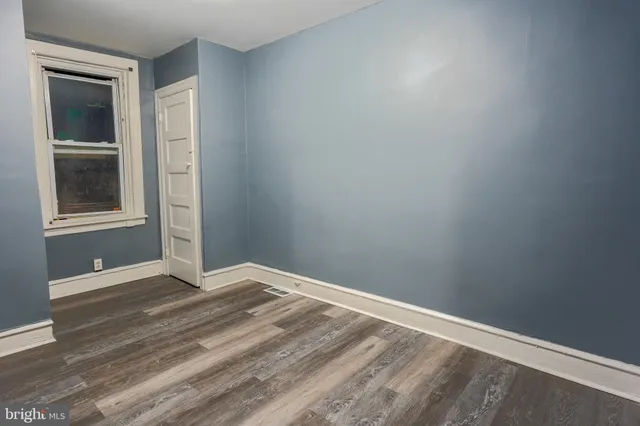 a view of an empty room with wooden floor and closet