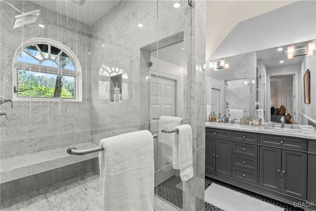 a spacious bathroom with a double vanity sink a large mirror a bathtub and next to a window