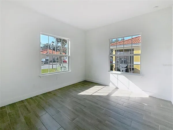 an empty room with wooden floor and windows