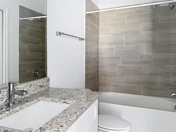 a bathroom with a granite countertop bathtub shower sink and toilet