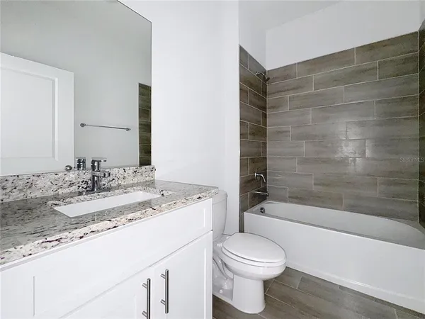 a bathroom with a granite countertop bathtub sink vanity mirror and toilet