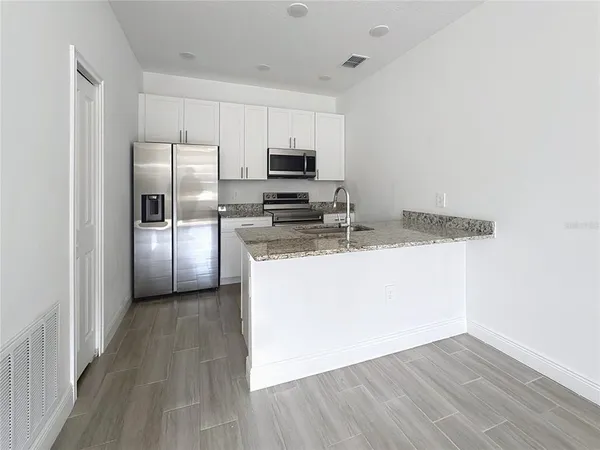 a kitchen with a refrigerator a microwave oven a sink and dishwasher with wooden floor