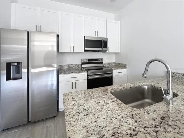 a kitchen with stainless steel appliances granite countertop a refrigerator a stove a microwave and a sink