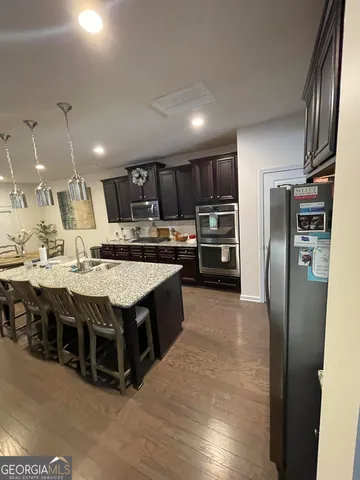 a kitchen with stainless steel appliances granite countertop a refrigerator a stove and a sink