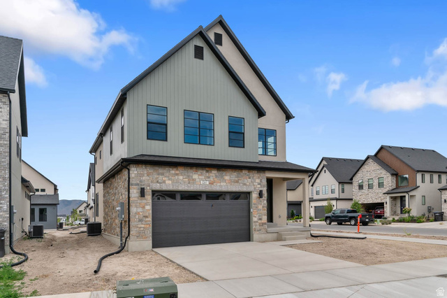 1567 North 3250 West Provo, UT 84601 - Photo 2 of 22 Modern two-story residence featuring a stone and siding exterior, an attached two-car garage with a dark panel door, and multiple large windows with dark frames