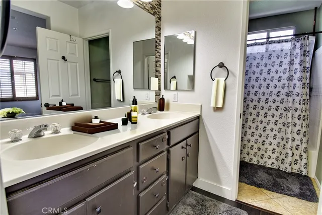 a bathroom with a double vanity sink a mirror a and a shower