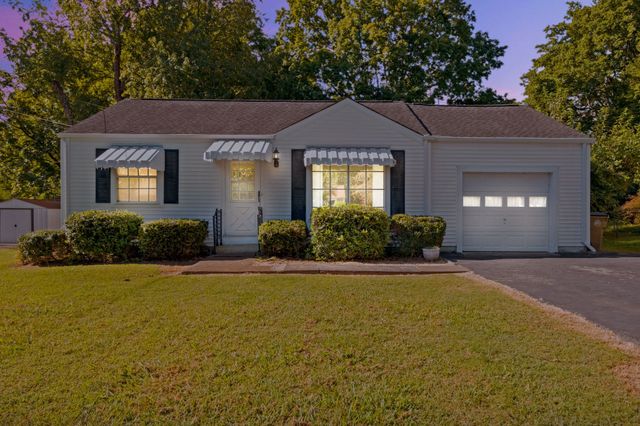a front view of a house with yard and trees