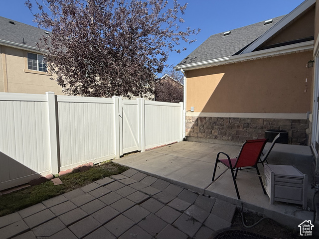 13548 South Villa Rosa Way Draper, UT 84020 - Photo 25 of 28 Paved patio featuring a stone veneer foundation, stucco exterior, and white privacy fencing with gate