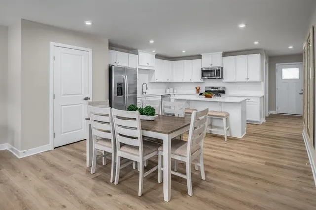 a kitchen with stainless steel appliances a dining table chairs and wooden floor