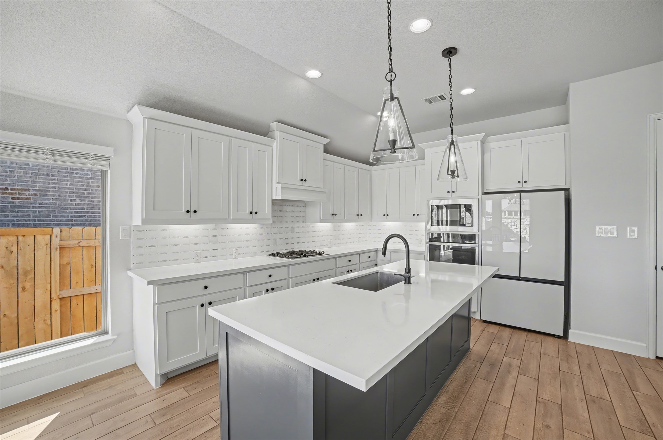 186 Prickly Poppy Loop Kyle, TX 78640 - Photo 7 of 40 a kitchen with a sink a stove a refrigerator and white cabinets with wooden floor