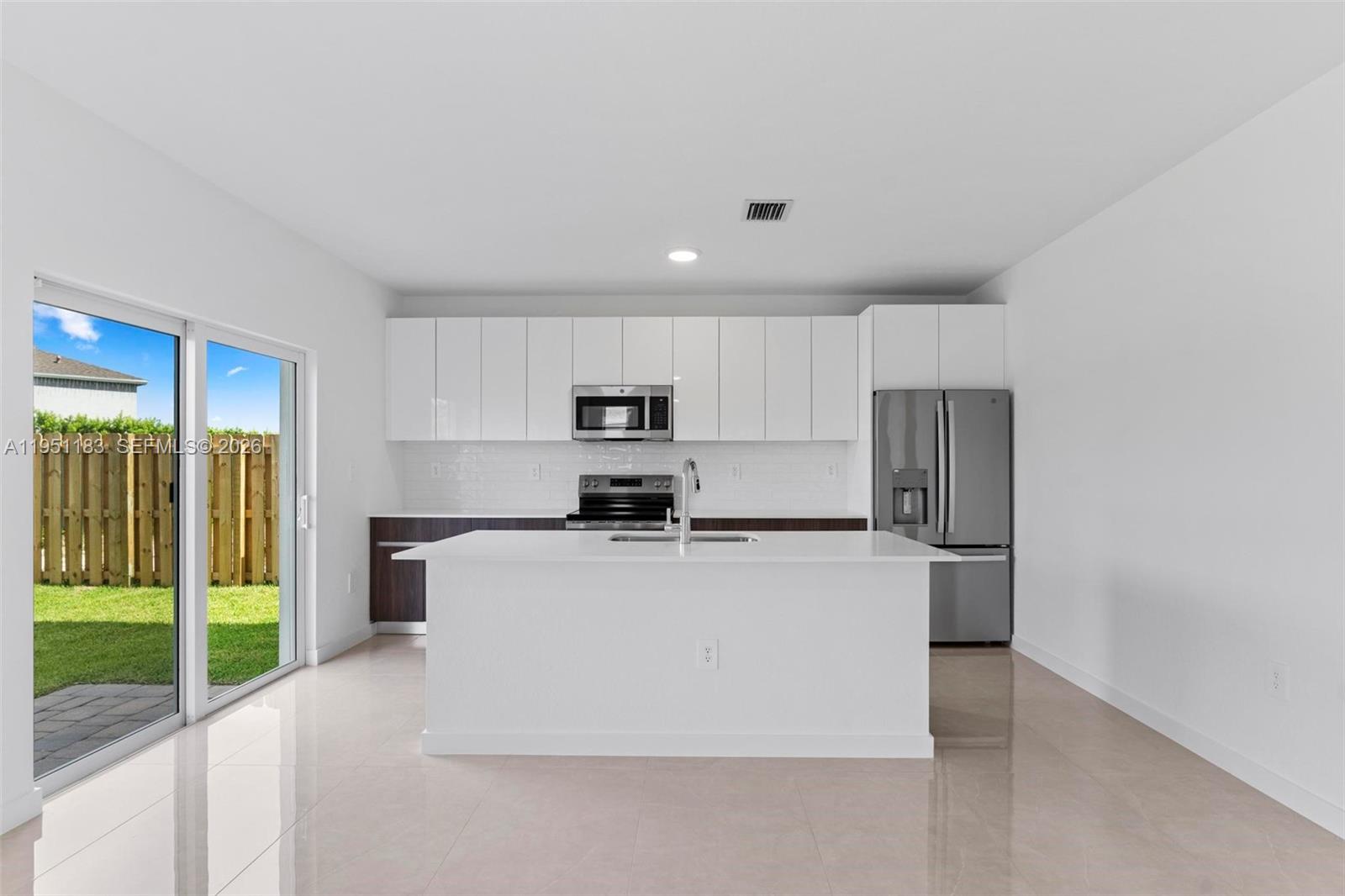 13361 Southwest 272nd Lane Homestead, FL 33032 - Photo 9 of 27 a kitchen with stainless steel appliances a refrigerator a stove top oven a sink and a large window