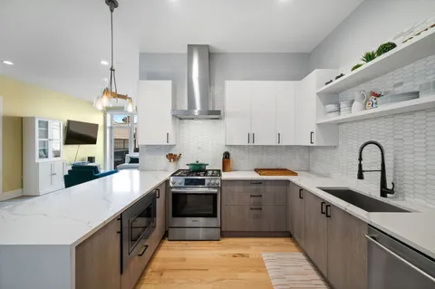 a kitchen with stainless steel appliances granite countertop a sink a stove and a wooden floors