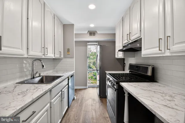 a kitchen with granite countertop a sink stove and cabinets