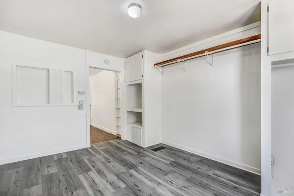 a view of a hallway with wooden floor and a bathroom