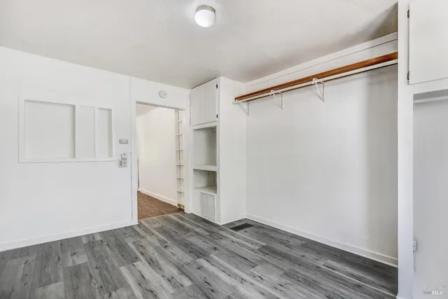 a view of a hallway with wooden floor and a bathroom