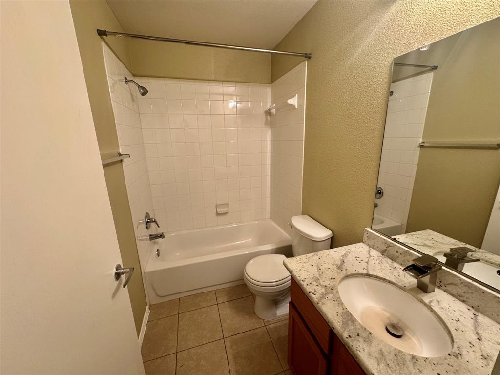 7812 Duber Lane Austin, TX 78747 - Photo 14 of 15 Bathroom featuring a white bathtub, ceramic tile shower surround, and a vanity with a granite countertop