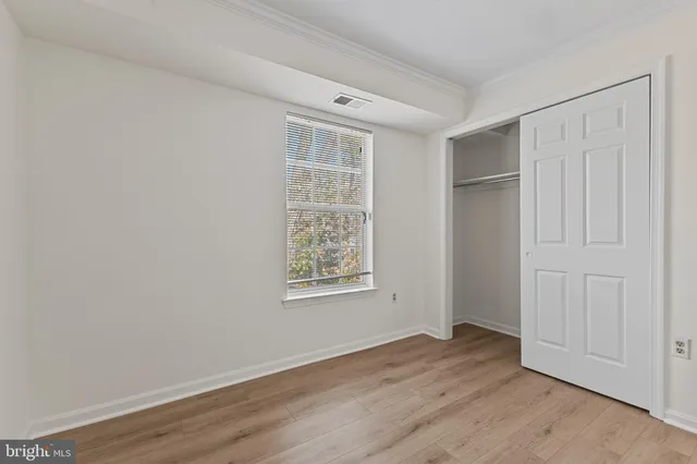 an empty room with wooden floor cabinet and windows