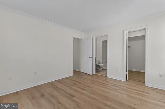 a view of an empty room with wooden floor & closet