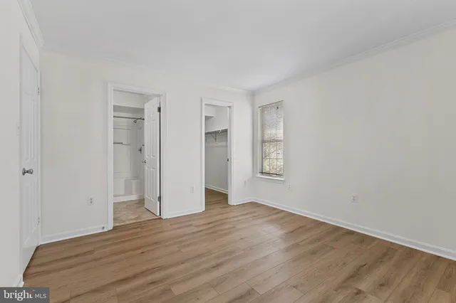 a view of an empty room with wooden floor and window