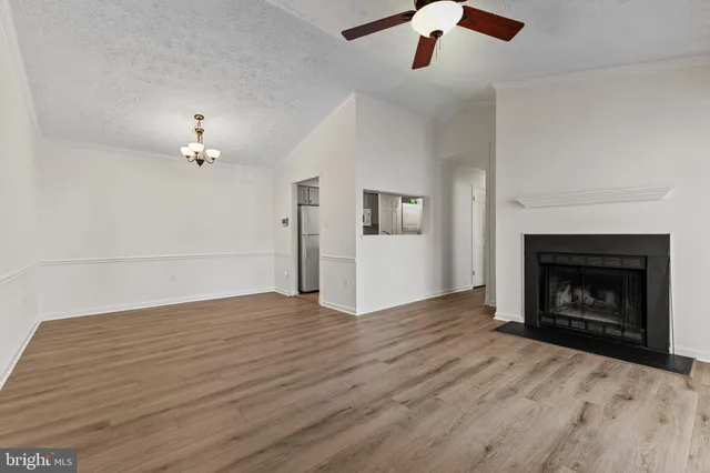 a view of an empty room with wooden floor fireplace and a window