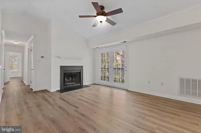 a view of an empty room with wooden floor fireplace and a window