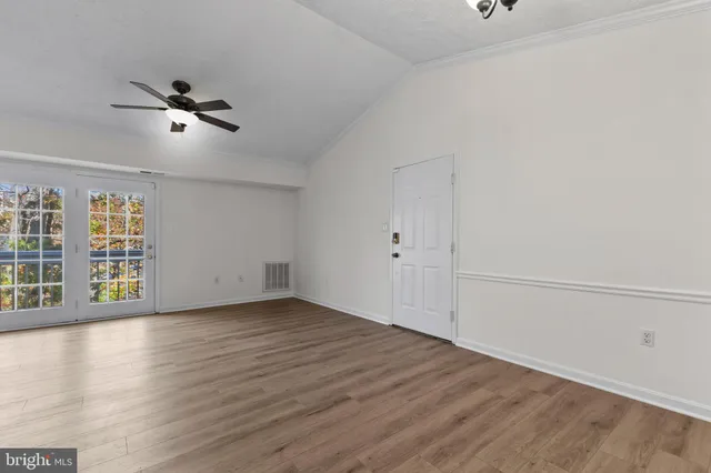 an empty room with wooden floor fan and windows