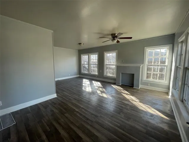 an empty room with wooden floor fireplace and windows