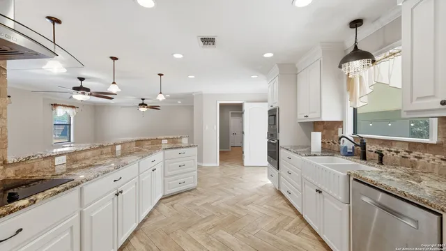 a large kitchen with granite countertop a large island in the center and stainless steel appliances