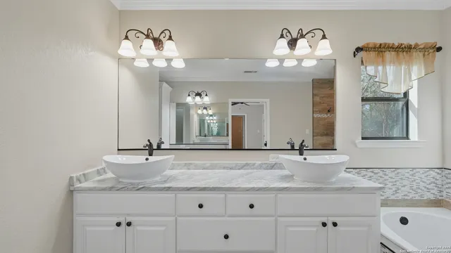 a bathroom with a granite countertop sink a large mirror and a window
