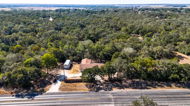 an aerial view of a residential houses with yard and trees