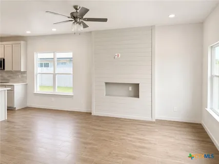 an empty room with wooden floor ceiling fan and windows