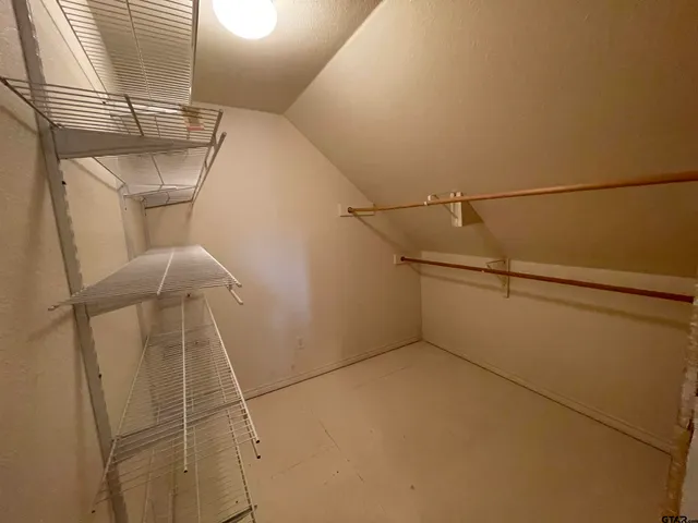 an empty room with chandelier fan and windows