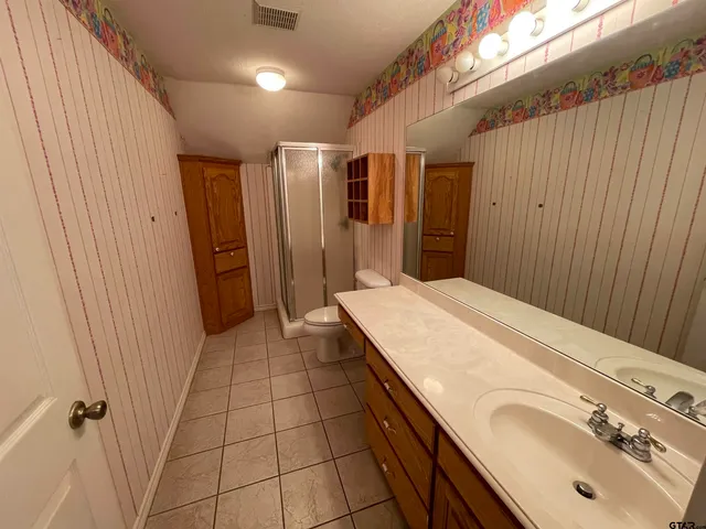 a view of an empty room with chandelier fan and wooden floor