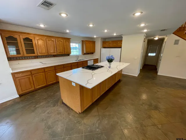 a large kitchen with stainless steel appliances a large counter top and a stove