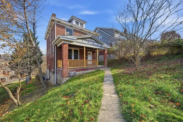 a front view of a house with a garden and trees