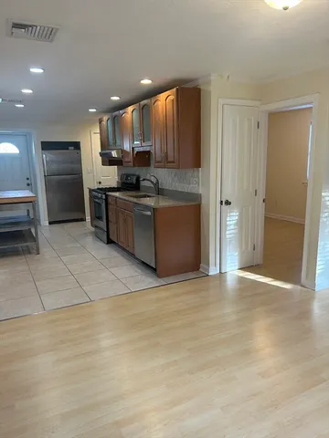 a large kitchen with stainless steel appliances granite countertop a refrigerator and a sink