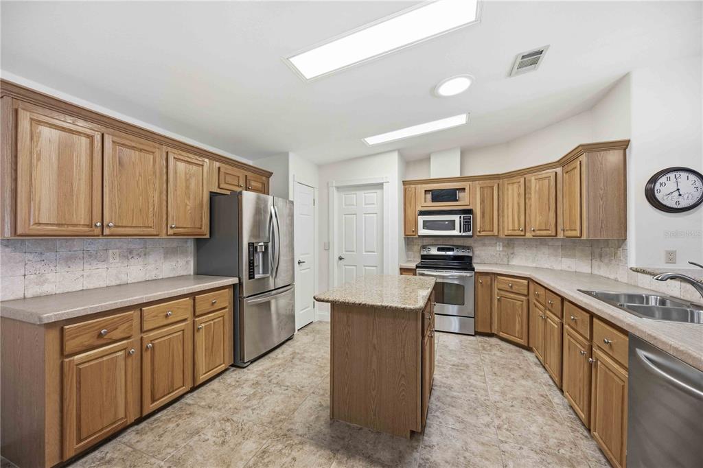 18 Emden Circle Punta Gorda, FL 33950 - Photo 21 of 61 a kitchen with stainless steel appliances granite countertop a stove top oven a sink dishwasher and a refrigerator with wooden cabinets