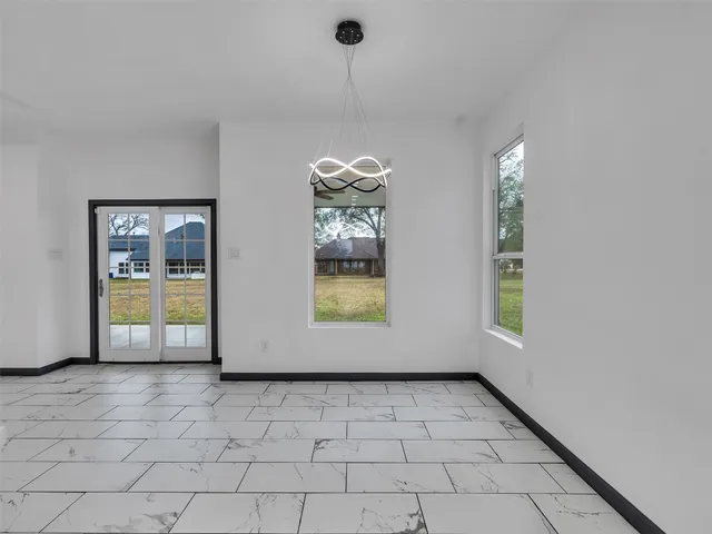 a view of an empty room with window and chandelier fan