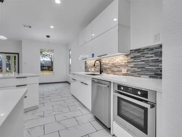 a kitchen with stainless steel appliances granite countertop a stove a sink and a microwave