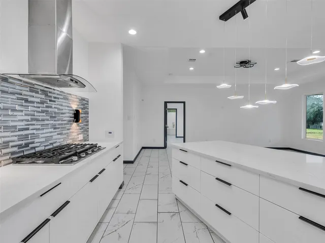 a kitchen with granite countertop a stove a sink and a refrigerator