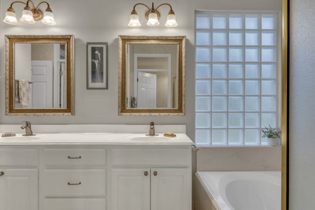 144 Cattle Trail Way Georgetown, TX 78633 - Photo 18 of 37 Double vanities and a relaxing tub beneath a privacy glass block window define this bathing space.