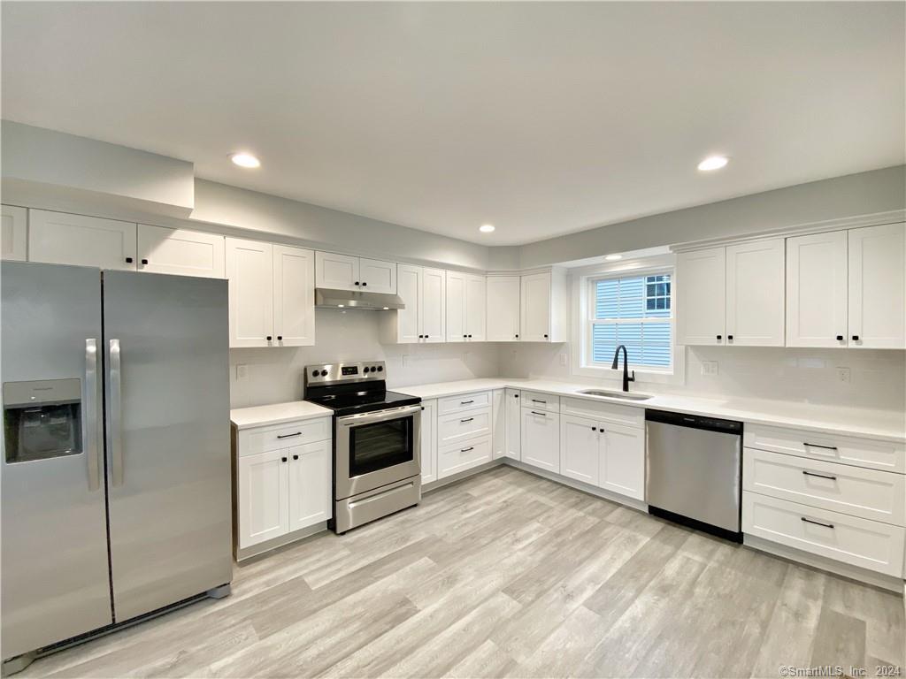 a large kitchen with cabinets stainless steel appliances and a window