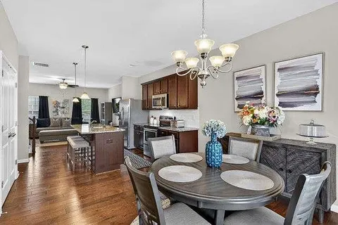 a view of a dining room with furniture a chandelier and wooden floor