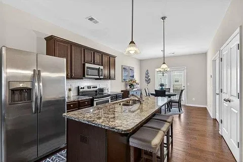 a kitchen with stainless steel appliances granite countertop a sink a microwave refrigerator and chairs
