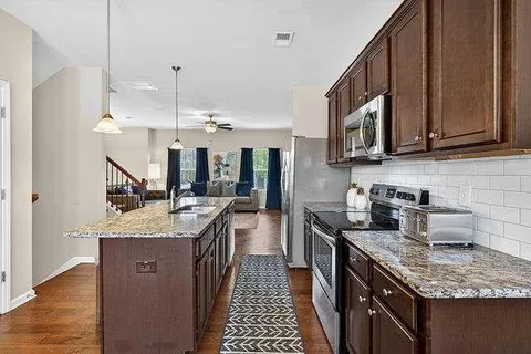 a kitchen with stainless steel appliances granite countertop a sink a stove and a wooden floors